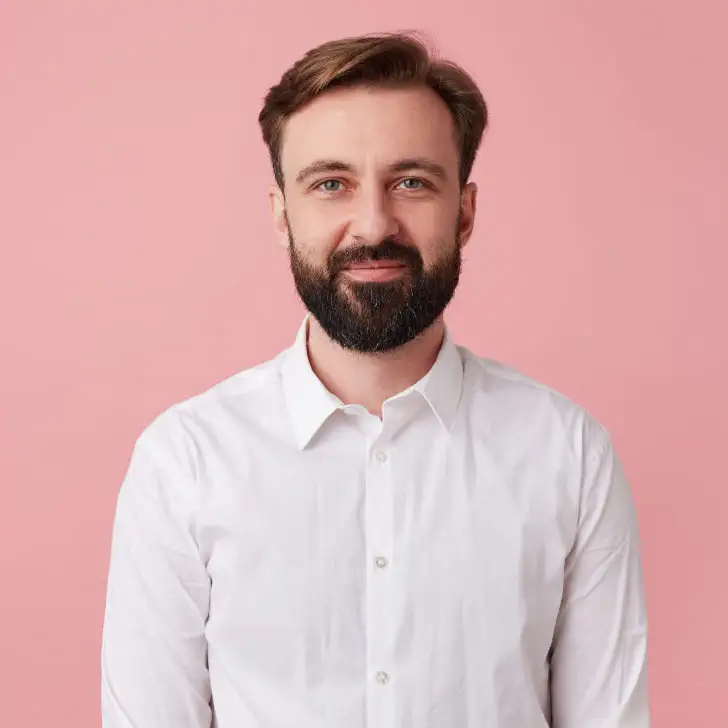 Mann mit Bart und weißen Hemd vor einem rosa Hintergrund
